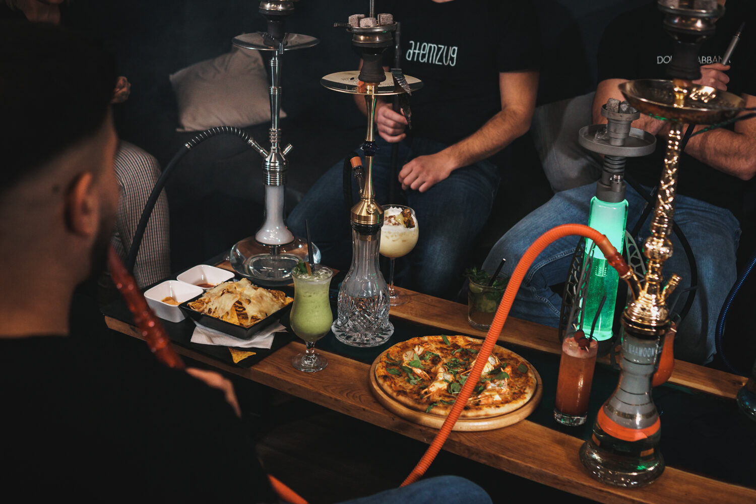 Gäste genießen Shishas, Cocktails und Pizza am Tisch