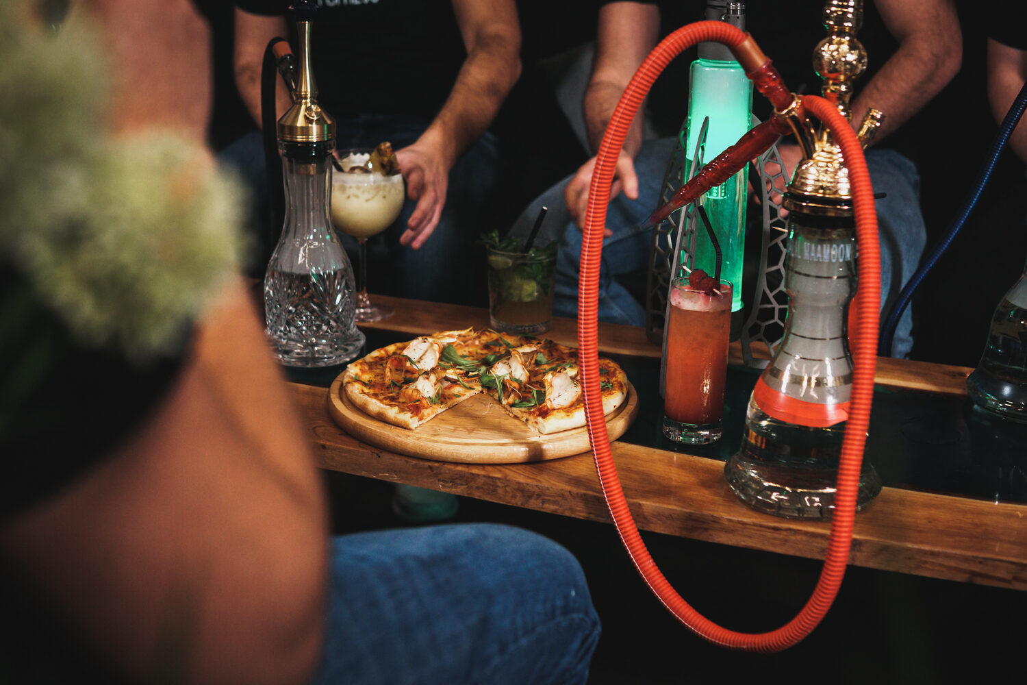 Shishas, Cocktails und Pizza auf dem Tisch